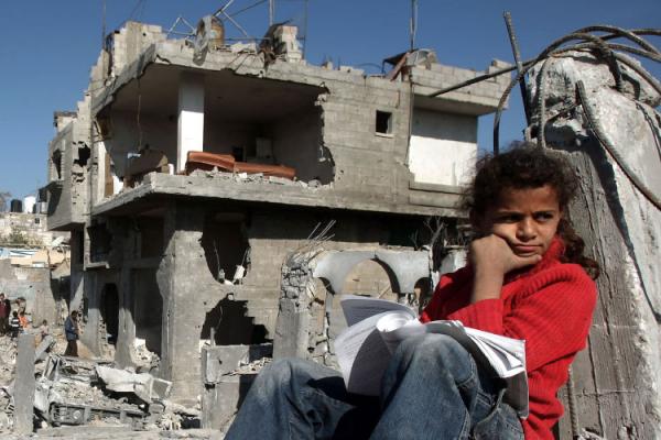 Palestinian teenager outside her destroyed home