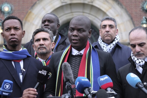 South Africa's Minister of Justice and Correctional Services Ronald Lamola, center, and Palestinian assistant Minister of Multilateral Affairs Ammar Hijazi, right, address the media outside the International Court of Justice in The Hague, Netherlands, Thursday, Jan. 11, 2024. The United Nations' top court opens hearings Thursday into South Africa's allegation that Israel's war with Hamas amounts to genocide against Palestinians, a claim that Israel strongly denies. (AP Photo/Patrick Post)